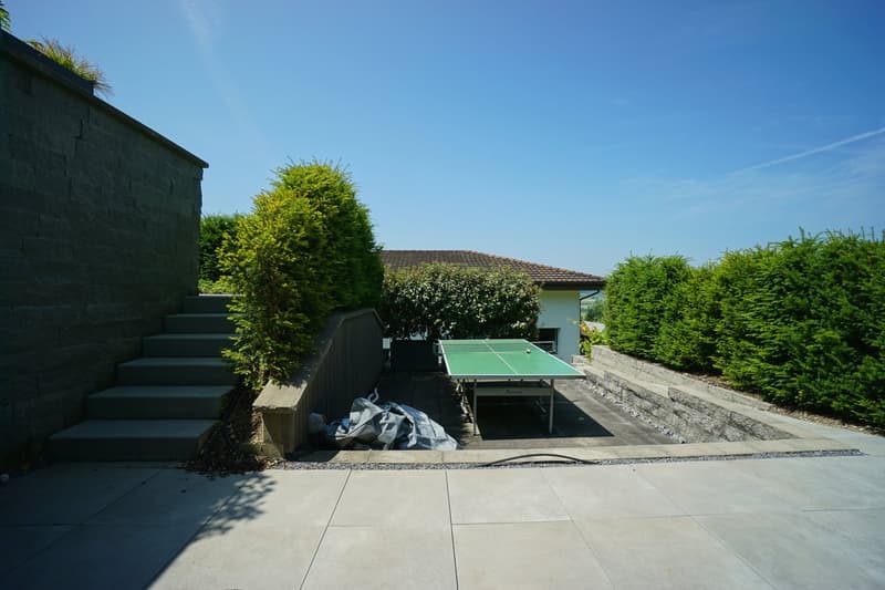 Table tennis table, stone wall, hedges, stairs, covered area