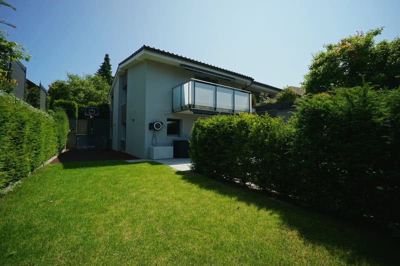 Modern house, white exterior, glass balcony, well-maintained garden, basketball hoop