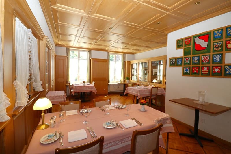 Spacious dining room with wooden paneled ceiling, large windows, wooden furniture, and decorative wall hangings
