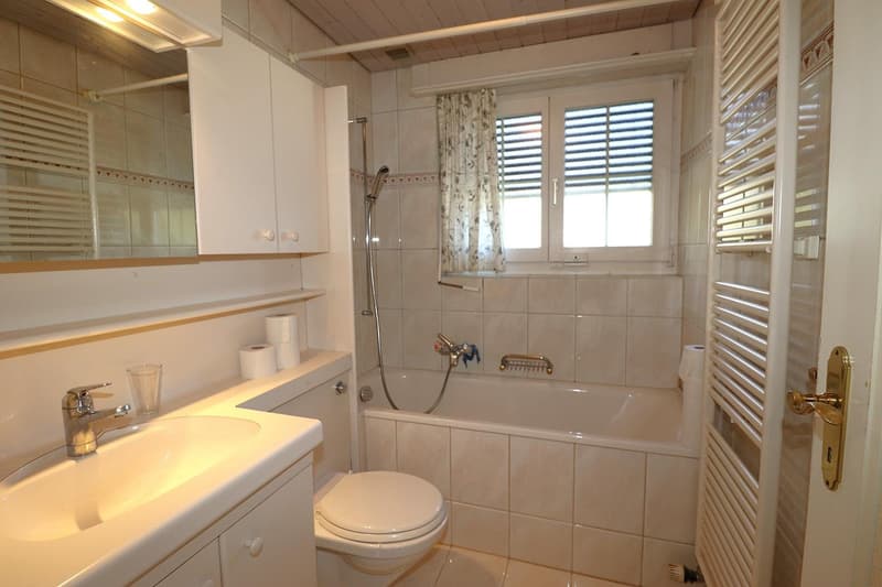 Bathroom with white tiles, toilet, sink, bathtub, shower, and a mirror