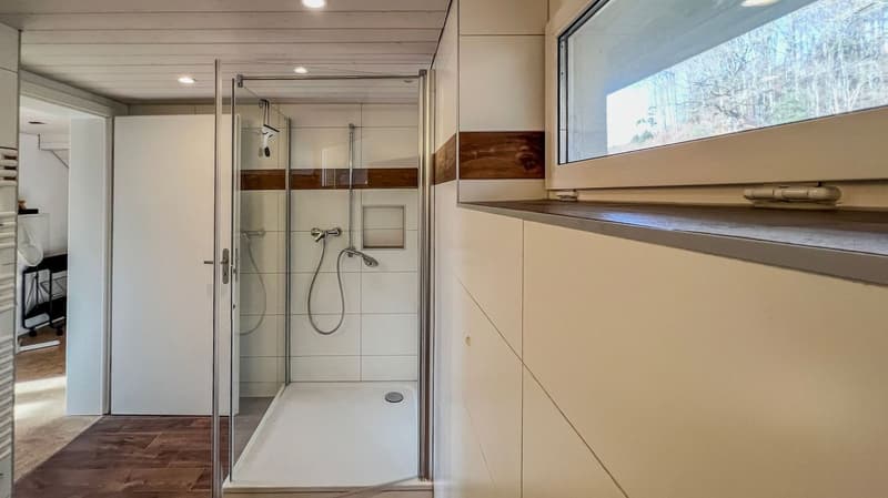 tiled floor, glass shower, metal drain, white cabinets, window