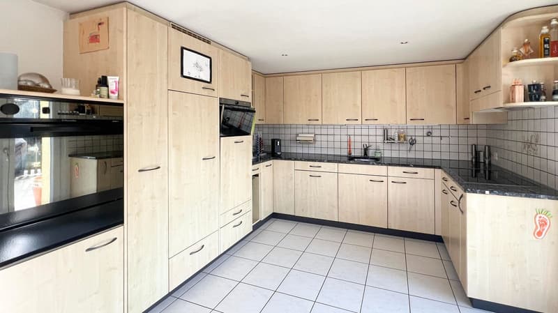 open kitchen with modern cabinets, tile floor, oven, sink, microwave, black countertops, appliances
