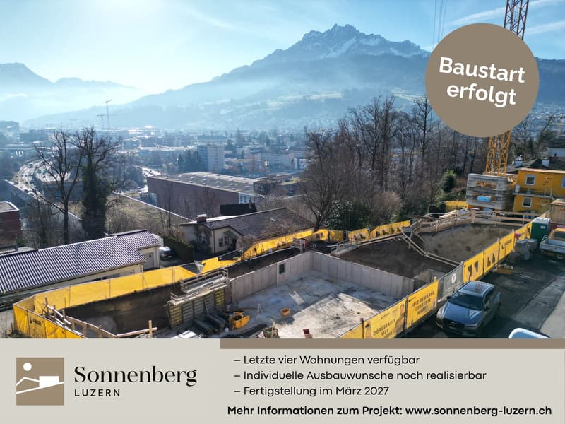 Construction site with a yellow wall, foundation walls, and buildings under construction in a mountainous area.
