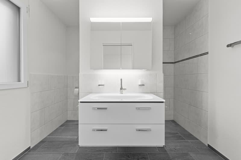 modern bathroom with white tiles, vanity unit, and a mirror