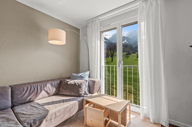 leather couch, wooden table, floor lamp, balcony, large window, view of mountains