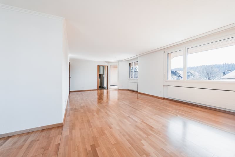 Helles Wohnzimmer mit Blick Richtung Küche und Balkon
