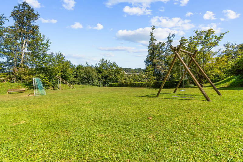 Grosse Grünfläche mit Spielplatz hinter dem Haus