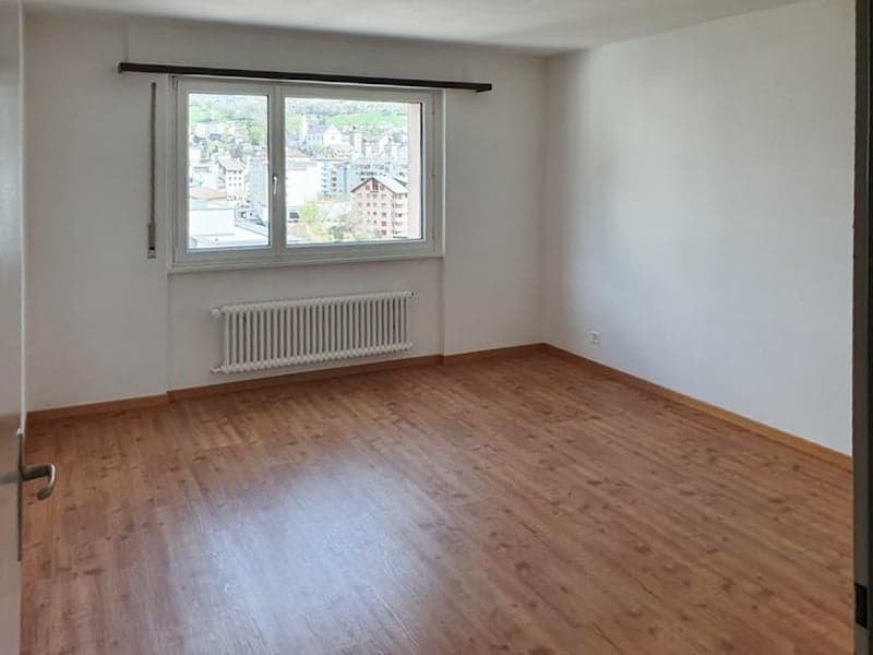 empty room, wooden floor, white walls, large window, white radiator