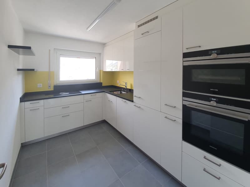modern kitchen with white cabinets, black countertops, yellow accent wall, Siemens oven, dishwasher, sink, faucet, window
