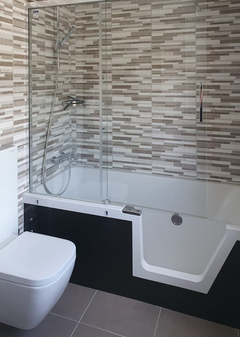 modern bathroom with a white bathtub, glass shower enclosure, white toilet, tiled walls, and a silver shower head