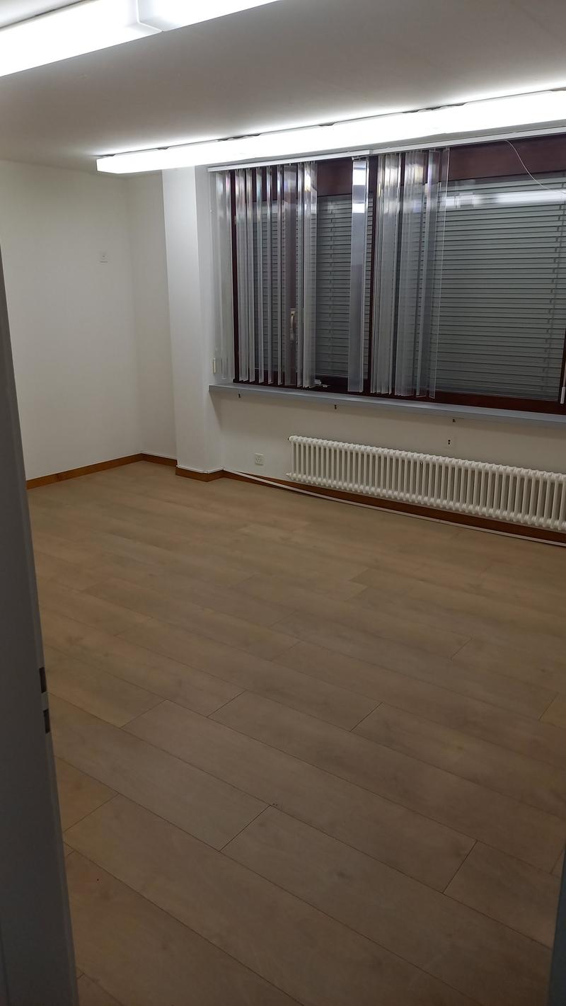 Empty room with hardwood flooring, white walls, and vertical blinds covering the windows.