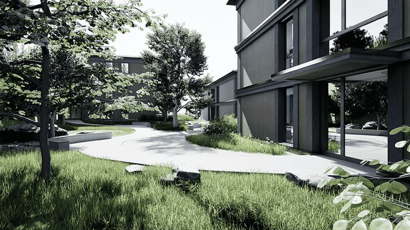 Modern building with glass windows, concrete pathway, grassy area, trees, rocks, and a bench
