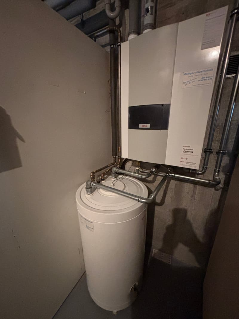 Water heater, pipes, and a white box with a label
