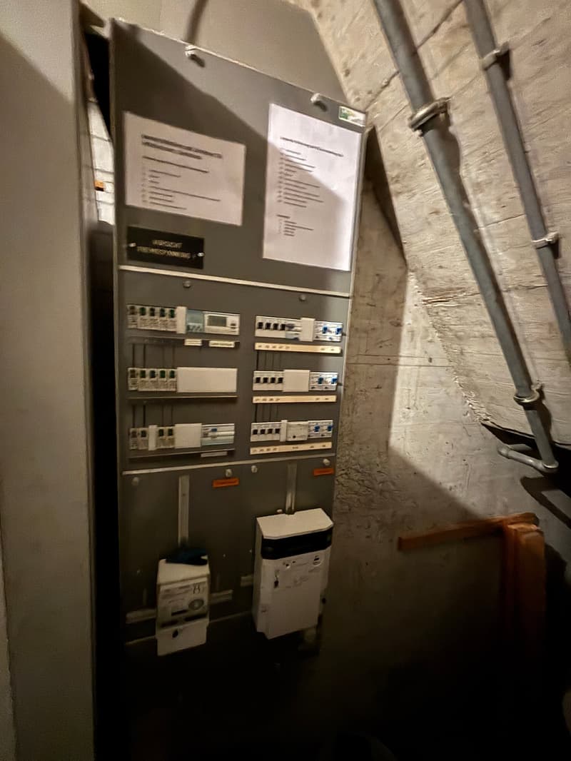 Electrical panel with multiple switches and meters, papers attached to the panel
