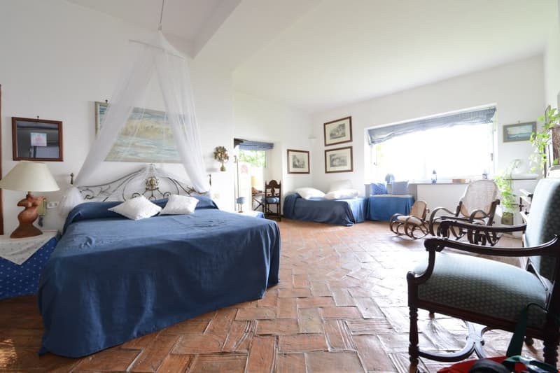 Spacious bedroom with two beds, wooden furniture, terrace, and decorative elements