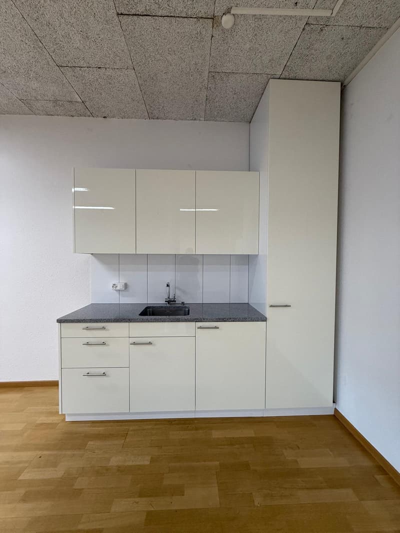 White cabinets, gray countertop, sink, white tile backsplash, wooden floor