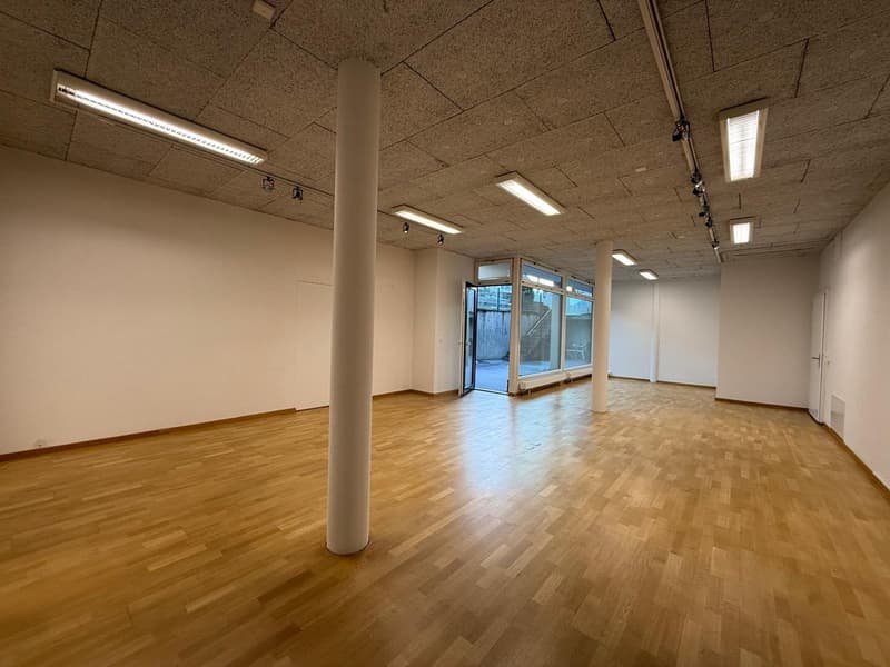 empty room with wooden floors, white walls, fluorescent ceiling lights, glass door