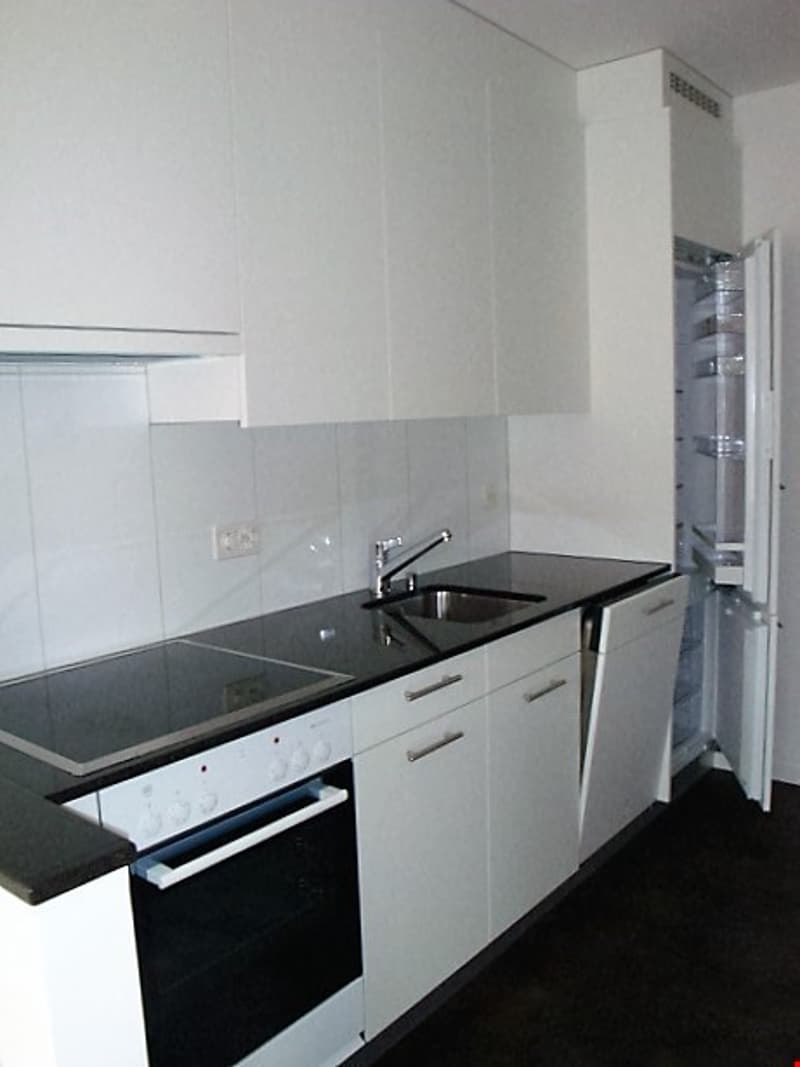 modern kitchen with white cabinets, black countertops, stainless steel sink, gas stove, oven, refrigerator, dishwasher, and a faucet