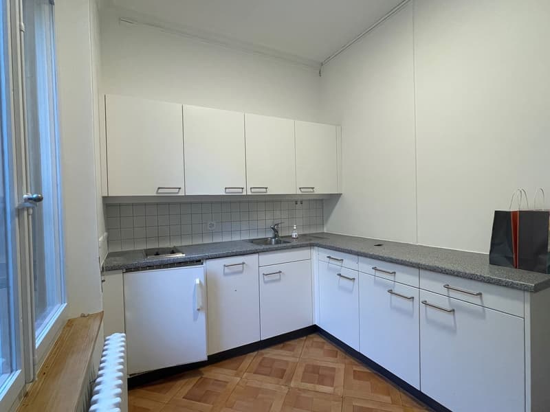 Kitchen with white cabinets, tiled backsplash, stainless steel sink, granite countertop, and white appliances.