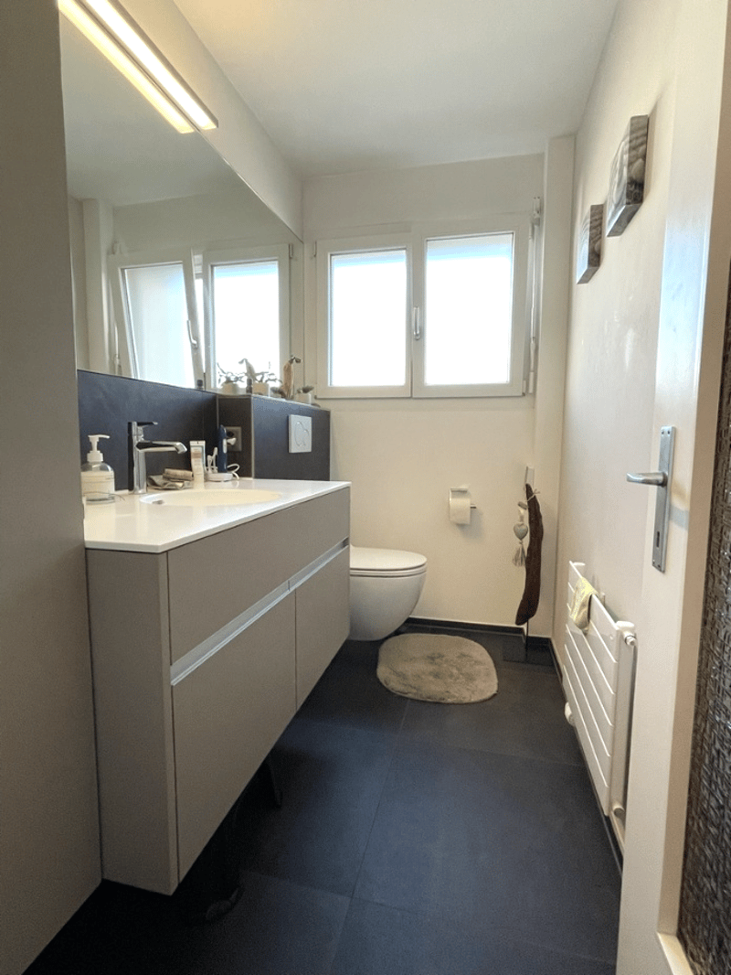 modern bathroom with white sink, mirror, toilet, and black floor