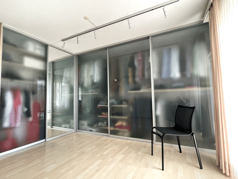 Empty room with wooden floor, glass sliding doors, and a black chair