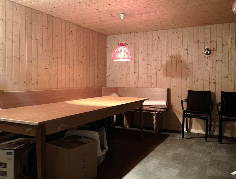 wooden walls, wooden table, wooden bench, chairs, lamp, boxes