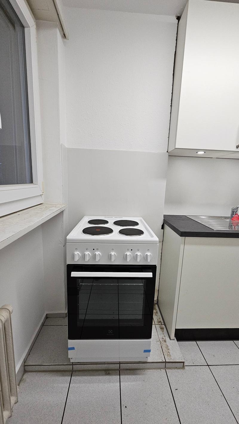 Compact kitchen, a gas stove, white cupboards, tile floor