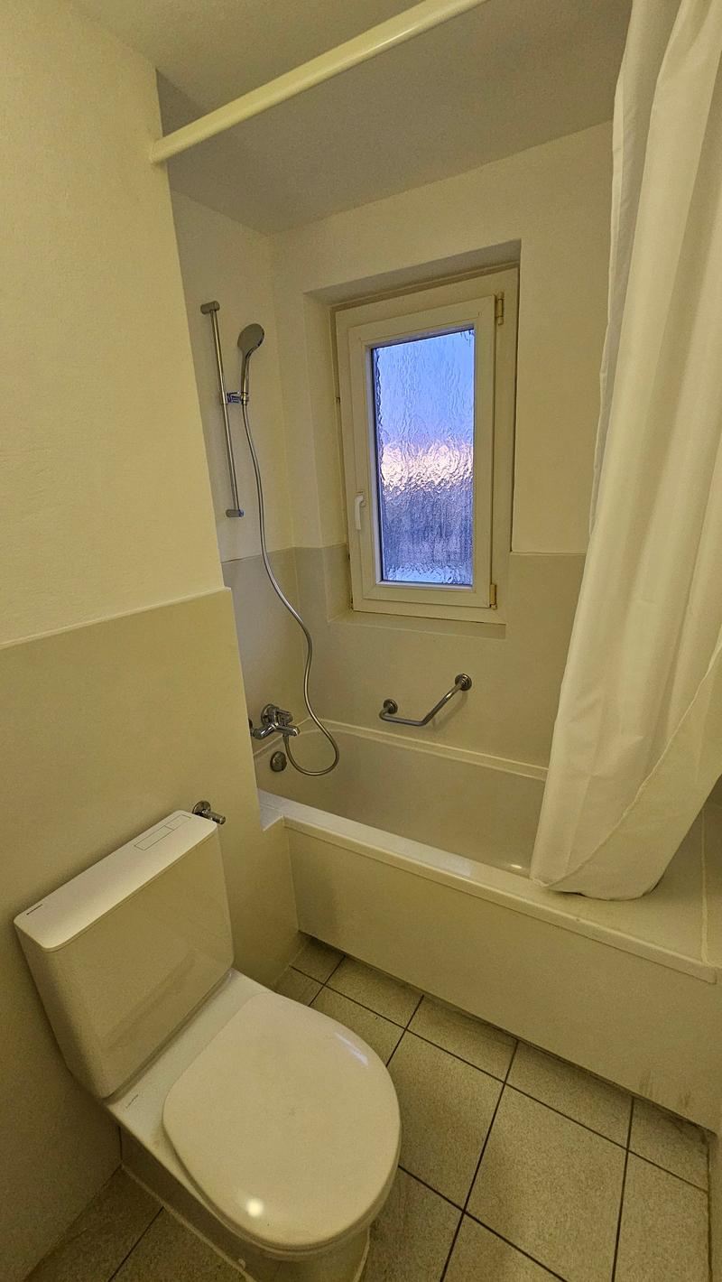 modern bathroom, white ceramic tile, modern bathtub, toilet, glass window, handheld shower
