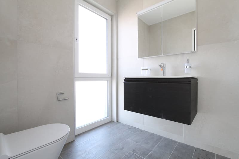modern bathroom with white toilet, black vanity, mirror, and tiled floor