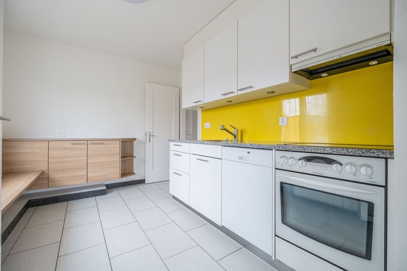 modern kitchen with white cabinets, yellow wall, stainless steel sink, dishwasher, oven, wooden bench, white tiles