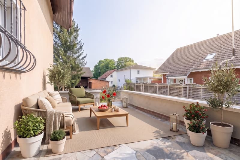 Terrace with beige rug, beige sofa, green armchair, wooden coffee table, potted plants, and lanterns