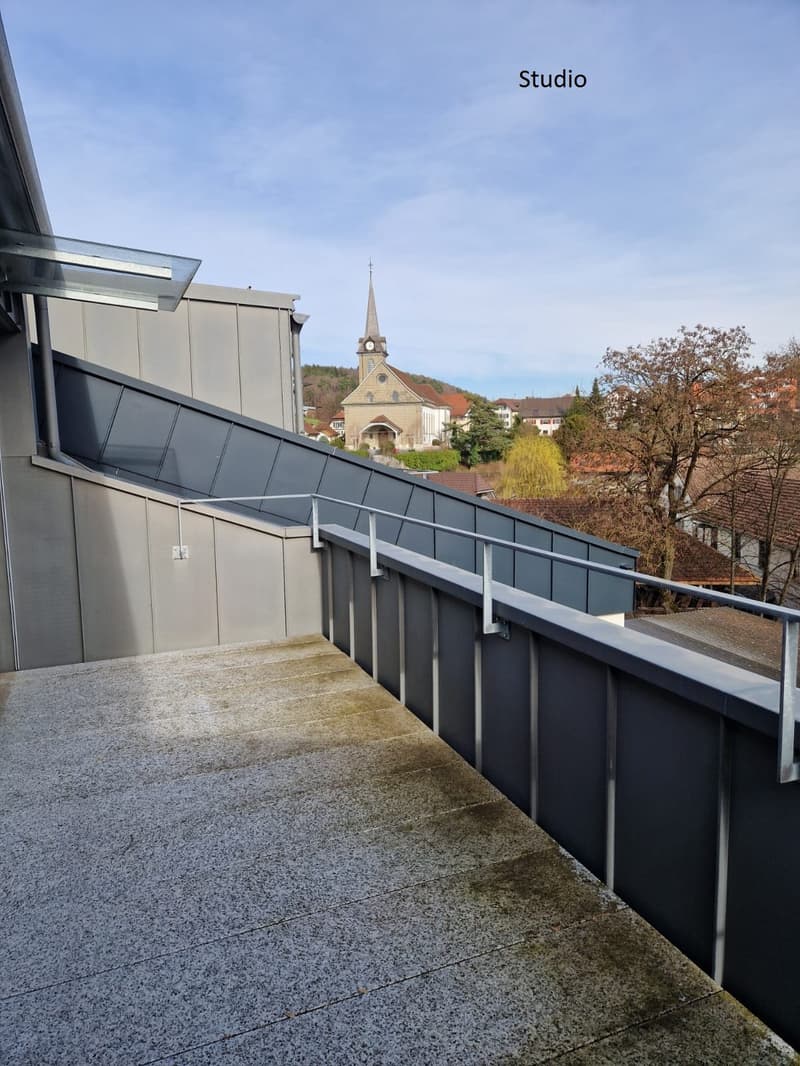 terrace with metal railing, tiled floor, distant view of church, trees and houses
