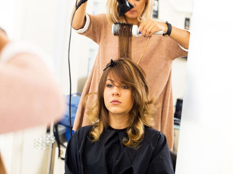 woman with black robe getting her hair done