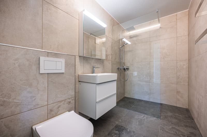 modern bathroom with white tiles, white sink, white toilet, glass shower enclosure, mirror