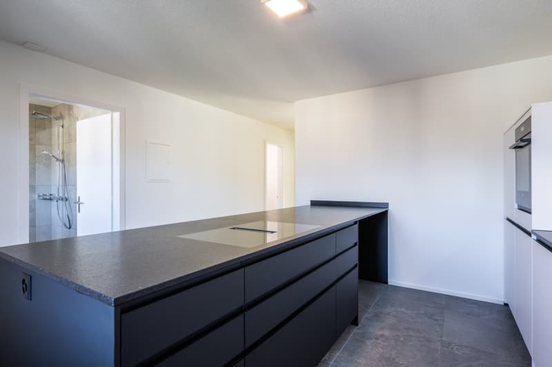 modern kitchen with island, black cabinets, granite countertop, built-in dishwasher, built-in washing machine