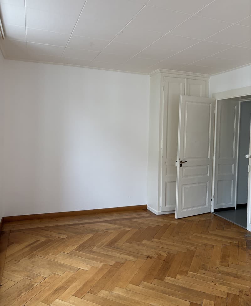 Empty room, white walls, wooden floor, open door, white ceiling, cabinet, hallway