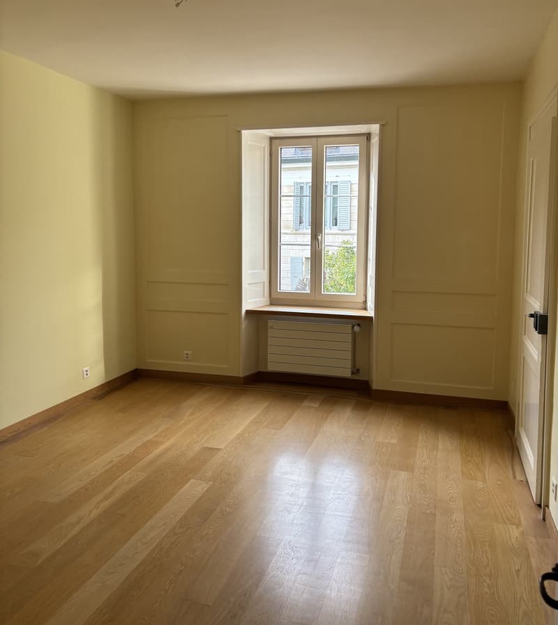 Empty room, large window, hardwood floor, white walls, radiator