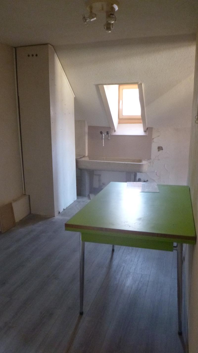 empty room, green desk, white sink, wooden floor, small window