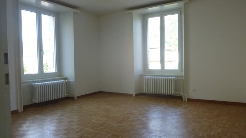 Empty room, white walls, wooden floor, radiators on both walls, two windows