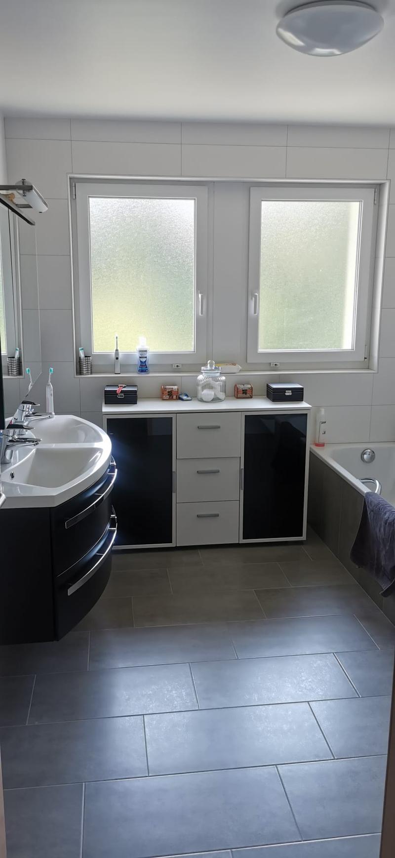 modern bathroom, white wall tiles, gray floor tiles, white sink, black cabinets, bathtub, double window
