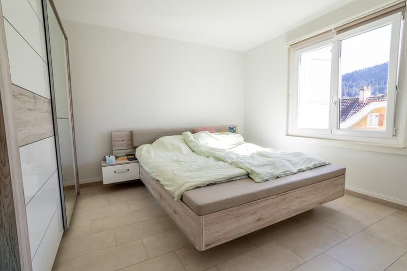 Bedroom with a bed, nightstand, and a window with a view of the mountains
