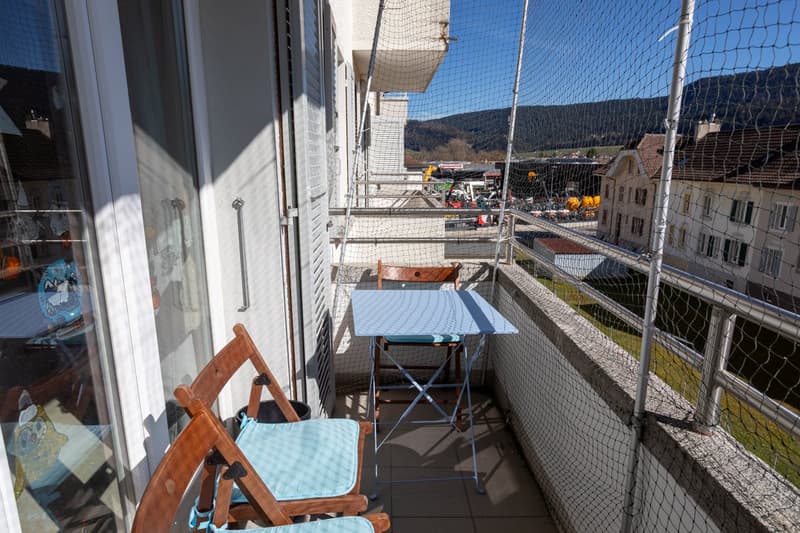 Balcony with table and chairs, fenced, view of mountains