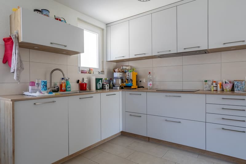 modern kitchen with white cabinets, wooden countertops, tiled floor, sink, faucet, dishwasher, washing machine, and various kitchen appliances and utensils