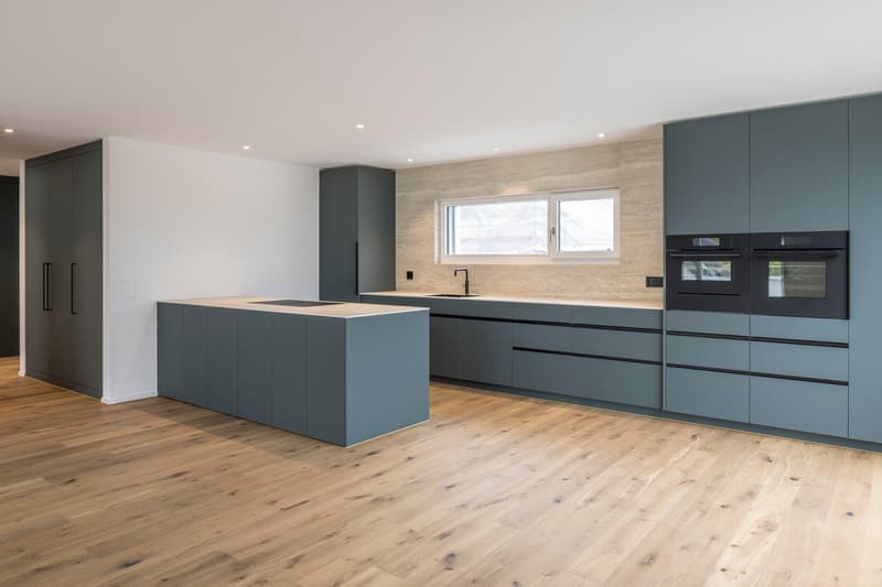modern kitchen with wooden floor, gray cabinets, island with stove, double oven, sink, window