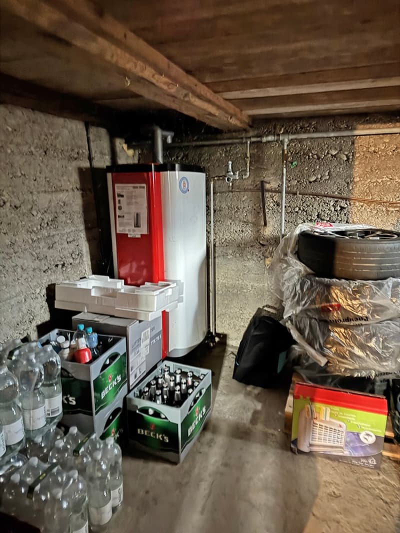 Basement room with a water heater, beer boxes, bottles, and a tire.