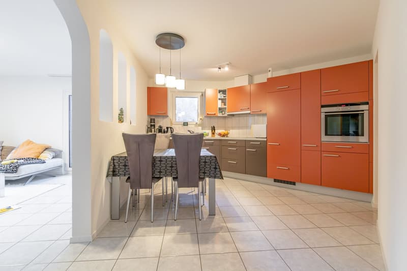 Modern kitchen, orange cabinets, dining table with four chairs, built-in oven, countertops, open area, tiled floor