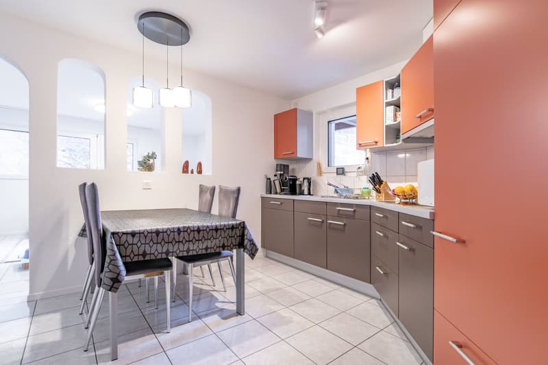 modern kitchen with island, white countertops, stainless steel appliances, open shelving, dining table and chairs, orange cabinets