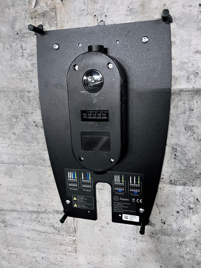 The image shows a black electronic device with various buttons, indicators, and connectors. The device appears to be a control panel or interface for some kind of electrical or electronic system. It has a circular dial or knob in the center, as well as se
