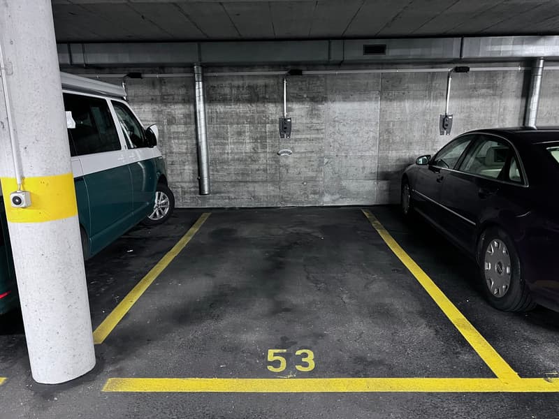 Concrete walls, yellow parking space markings, two cars parked in the garage