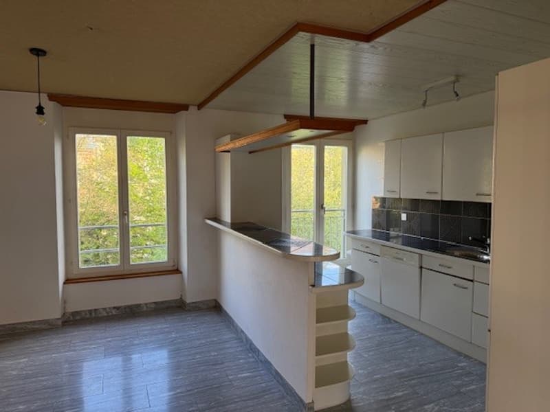 kitchen with island, white cabinets, black countertops, large windows, balcony
